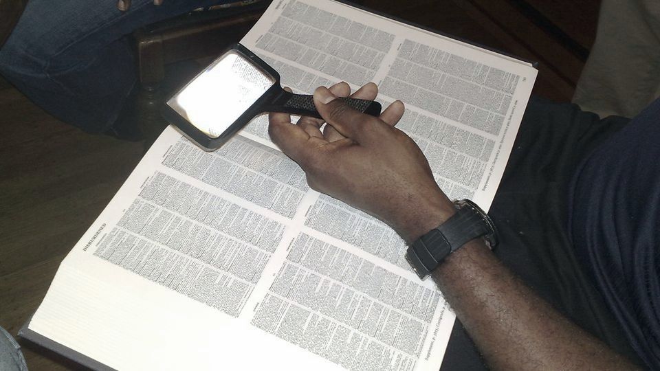 Reading small print on a page through a magnifying glass