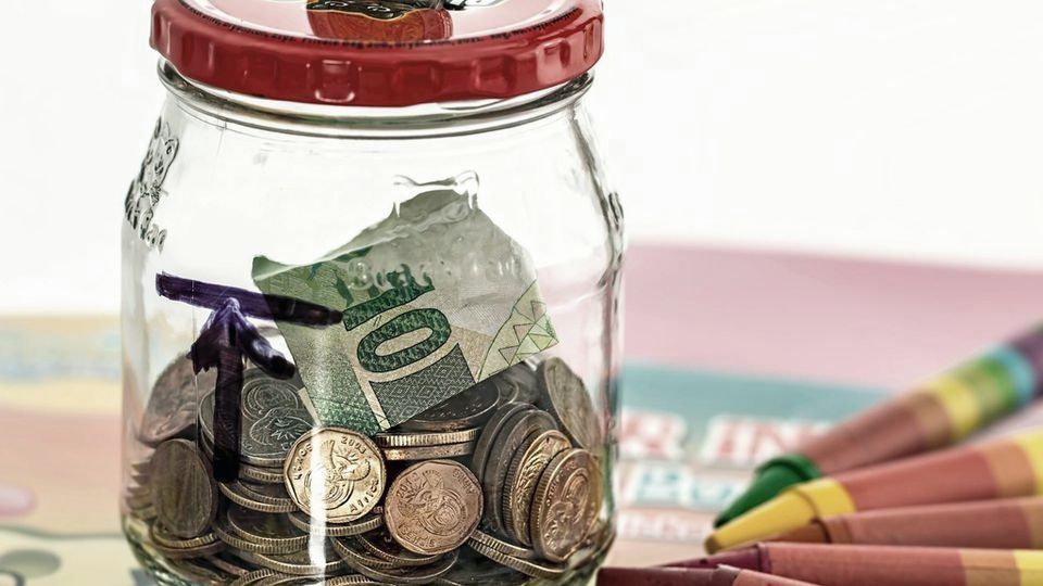 A glass jar holding coins and banknotes