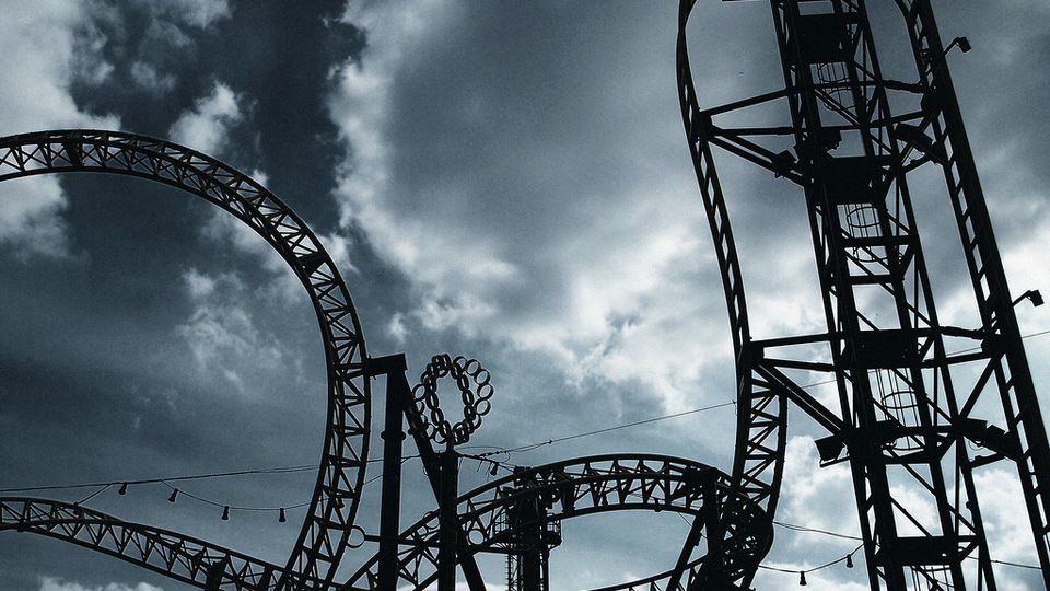 Roller coaster track silhouetted against a cloudy sky