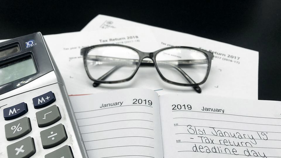 A calculator, reading glasses and a diary page noting a tax deadline