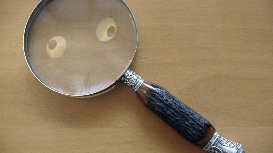 A magnifying glass lying on a wooden desk