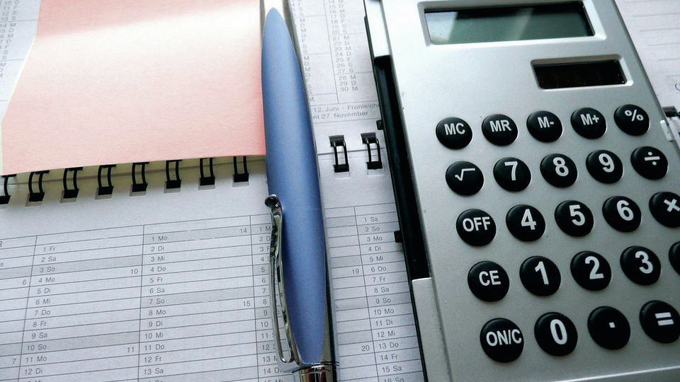 A calculator and pen resting on a sheet of figures